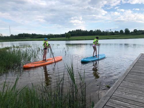 two people are standing on paddle boards on a lake at Dzirnavkalns in Cesvaine