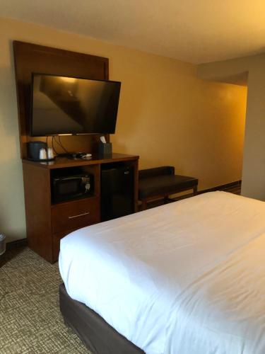 a hotel room with a bed and a flat screen tv at Wingate by Wyndham Grove City in Grove City