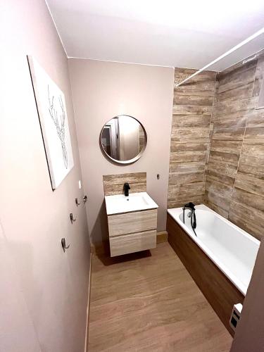 une salle de bain avec un lavabo, une baignoire et un miroir dans l'établissement Ma Montagne Chic 3, à La Bresse