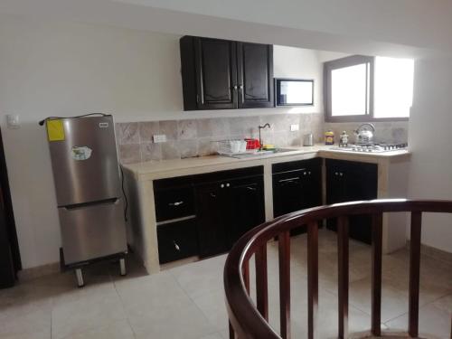 a kitchen with black cabinets and a stainless steel refrigerator at Departamento vacacional in Guayaquil