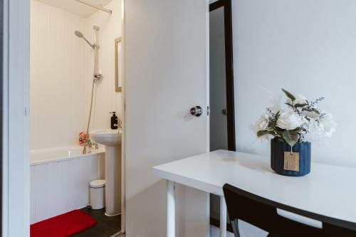 a bathroom with a white table with a vase of flowers at Whitechapel en-suite beds to stay in London