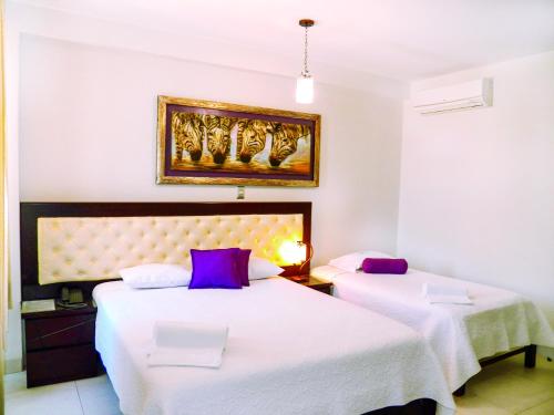 a bedroom with two beds and a painting on the wall at Cacique Hotel in Piura