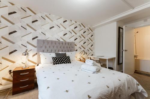 a bedroom with a large white bed with a wooden cabinet at Whitechapel en-suite beds to stay in London