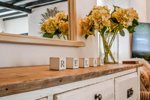 a counter with a mirror and flowers in a vase at Briardene Cottage - A Superb Bijou Retreat with Jacuzzi near an Excellent Village Pub in Yelverton