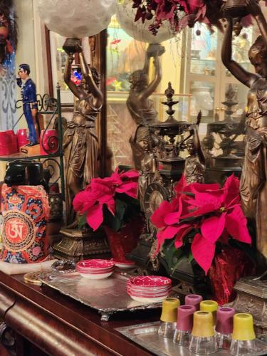 a table with red flowers and statues on it at House of 1833 Bed and Breakfast in Mystic