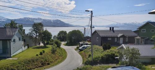 a residential street with houses and mountains in the background at Aurora rooms for rent nr2 We are doing privet Northen lights trips, reindeer trip and Fjord sommaroy trip in Tromsø