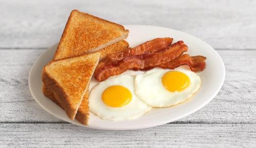 a plate of eggs bacon and toast on a table at Antonio Residence in Škvorec