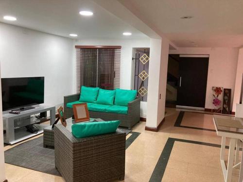 sala de estar con sofá verde y TV en Departamento Cerca a la Terminal del Sur MAG201, en Medellín