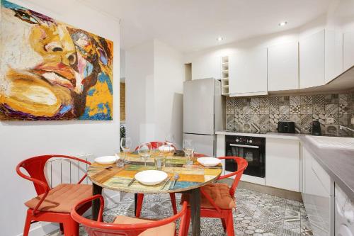 une cuisine avec une table, des chaises et un tableau dans l'établissement Cosy apartment - 6P-2BR - République, à Paris