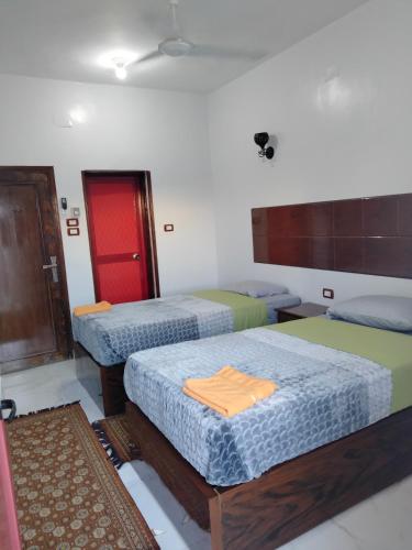 a room with three beds and a red door at Jamaica Guest House in Aswan