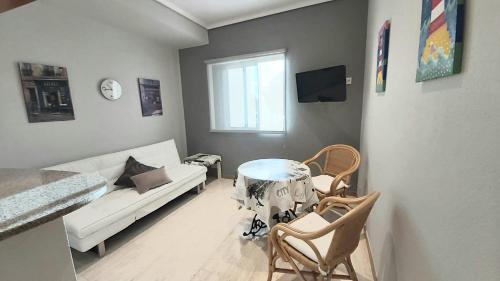een woonkamer met een bank en een tafel en stoelen bij Apartamento Samil Primera Línea de Playa 2M in Vigo