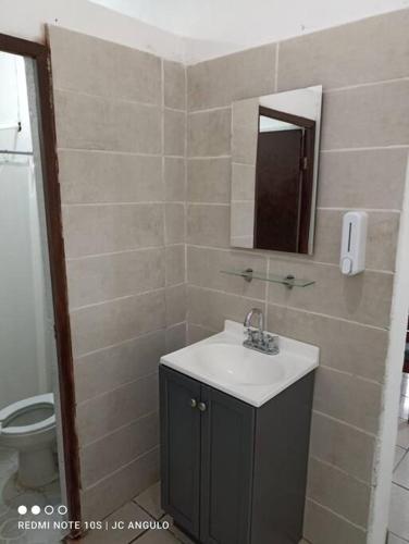 a bathroom with a sink and a mirror and a toilet at Casa sencilla, primer piso bien ubicada in Mazatlán