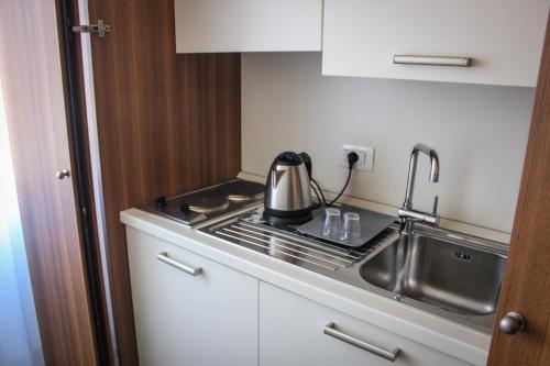 a kitchen with a sink and a tea kettle on the stove at Hotel Centrale in Este