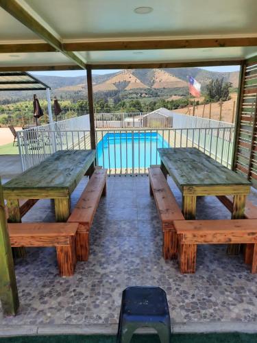 two wooden benches sitting in front of a pool at Hospedaje vista hermosa in Quillota