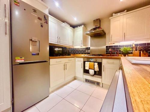 a kitchen with white cabinets and a stainless steel refrigerator at Sensational 3-Bed Home Near Bluewater in Kent