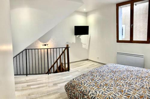 une chambre avec un lit et un escalier avec une télévision dans l'établissement Duplex au coeur du village, à Les Mées