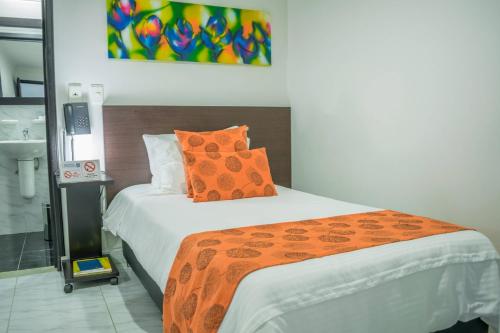 a bedroom with a bed with an orange comforter at Hotel Montes De La Castellana in Armenia