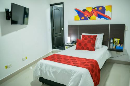 a bedroom with a large bed with a red pillow at Hotel Montes De La Castellana in Armenia