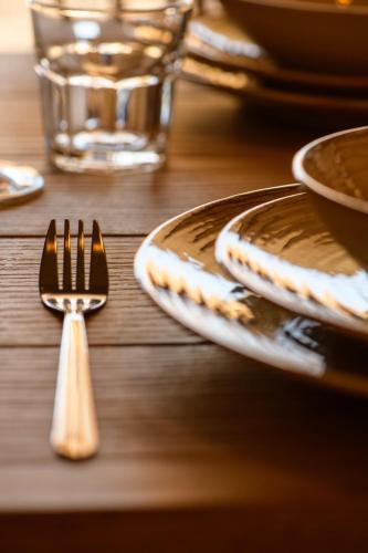 a wooden table with plates and a fork on it at Homa Serifos pool villas in Serifos Chora