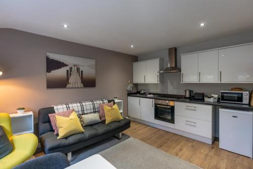 a living room with a couch and a kitchen at The Hive Apartment in Marple