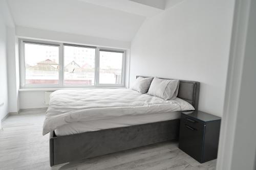 a white bedroom with a large bed and two windows at Bright and cozy apartment nr. 5 in Chişinău