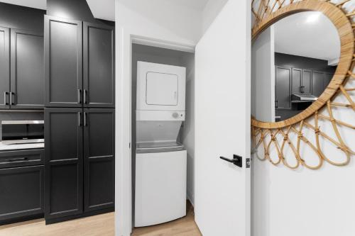 a kitchen with black cabinets and a mirror at Stonewall Suites in Montréal
