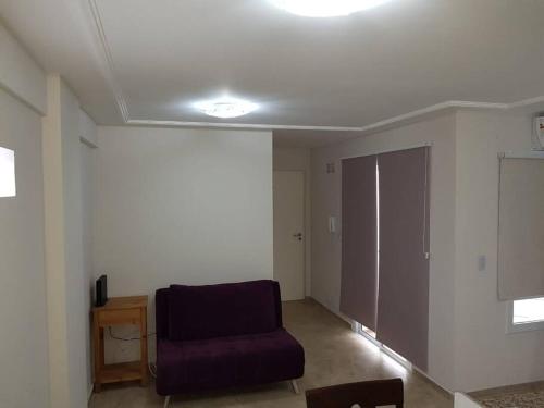 Sala de estar con silla morada y puerta en Piscis II en Córdoba