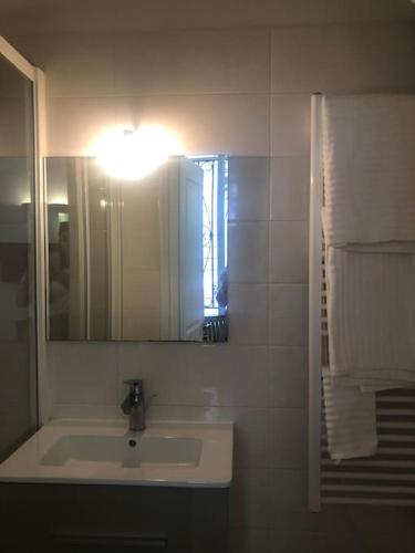 une salle de bain avec un lavabo, un miroir et des serviettes dans l'établissement Studio de Charme de Verneuil, à Paris