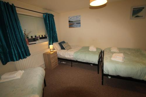 a room with three beds and a window with green curtains at Stirling House in Sheffield