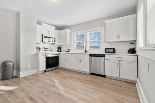 a white kitchen with white cabinets and a wooden floor at Cozy 4B Retreat Near Uptown King Beds Sleeps 12 in Charlotte