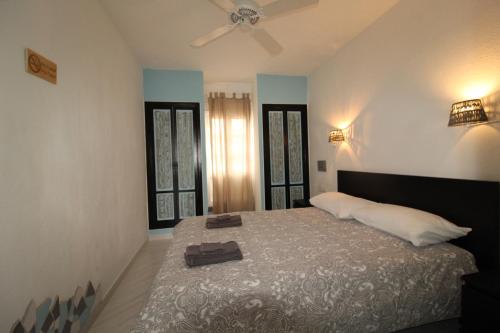 a bedroom with a bed with a fan and two windows at Casa Maria N2 Montecastillo in Caleta De Fuste