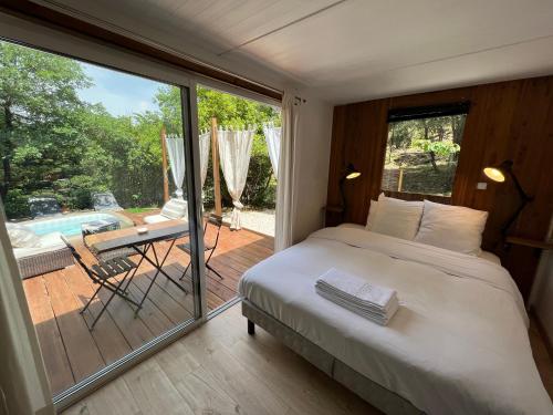 1 dormitorio con 1 cama y balcón con piscina en Superbe Cabane JACUZZI JARDIN CLIM WIFI PARKING, en Meyreuil