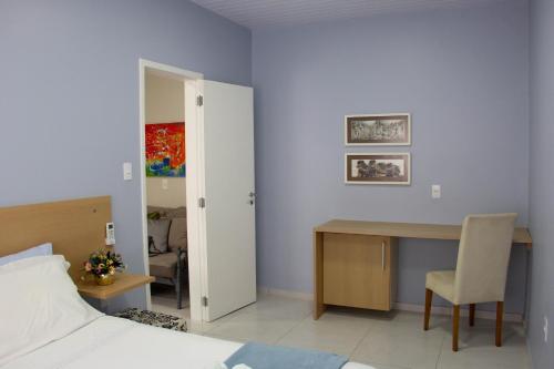 a bedroom with a bed and a desk with a chair at Solar da Lorena in Florianópolis