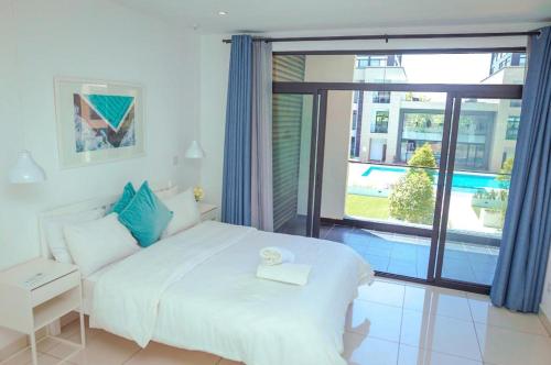 The VVIP Luxury Apartments @ Gardens في آكرا: غرفة نوم بسرير ابيض ونافذة كبيرة