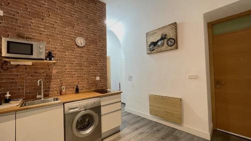 eine Küche mit einer Waschmaschine und einer Ziegelwand in der Unterkunft Casa Palacio in Sanlúcar de Barrameda