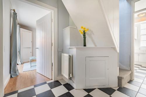 a white hallway with a vase of yellow flowers on a counter at Chadbury House Annexe in Evesham