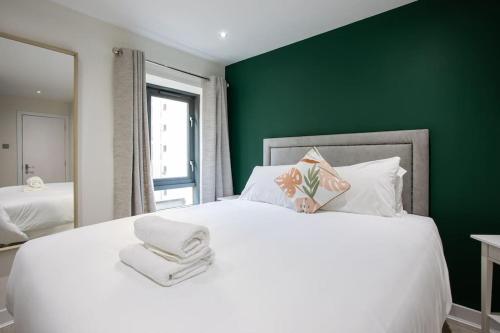 a bedroom with a large white bed with a green wall at Luxury, Sleeps 6, City Centre in Belfast