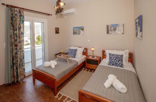 1 dormitorio con 2 camas y ventana en Ruby's summer house with spacious garden and free parking, en Gavrion