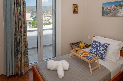 a room with a bed with a table and a window at Ruby's summer house with spacious garden and free parking in Gavrion
