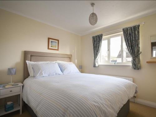 a bedroom with a large white bed with a window at Mead Cottage in Bridport