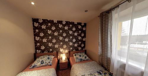 two beds in a room with a wall with flowers at Apartment Karkonosz in Szklarska Poręba