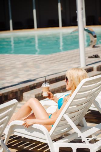 a woman sitting in a lounge chair with a drink at Готель Гармонія. Термально-оздоровчий комплекс. in Uzhhorod