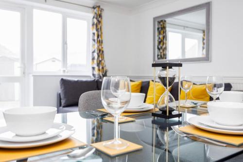 a dining room table with glasses and dishes on it at Lovely 2 Bed House in Grays. in Grays Thurrock