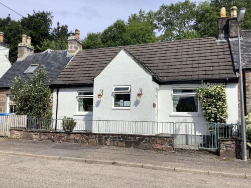 a white house with a black roof at Moriston Cottage in Lochcarron