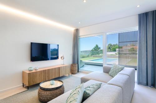 a living room with a couch and a flat screen tv at Mar a Vista - Condominium with Pool, Gym and Sea Views in Nazaré