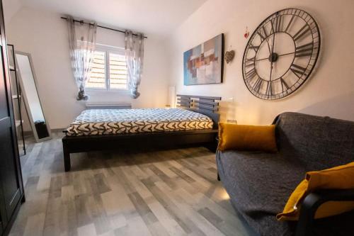 1 dormitorio con 1 cama y reloj en la pared en Le nid cosy d'Obernai /2min centre ville/parking en Obernai