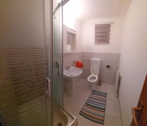 een badkamer met een douche, een toilet en een wastafel bij Guesthouse Kusić in Kupres