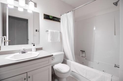 y baño blanco con lavabo, aseo y ducha. en NN - Pink Palace - Downtown 1-bed 1-bath, en Whitehorse