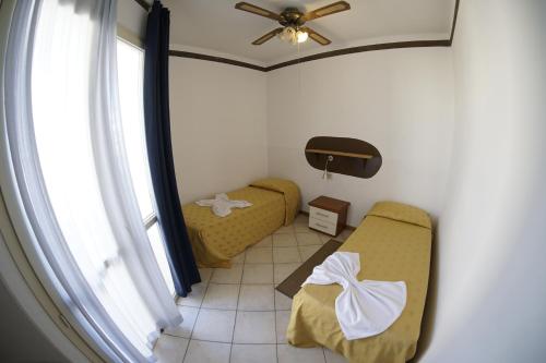 um pequeno quarto com 2 camas e uma ventoinha de tecto em Estoril Hotel - Apartments em Sal Rei