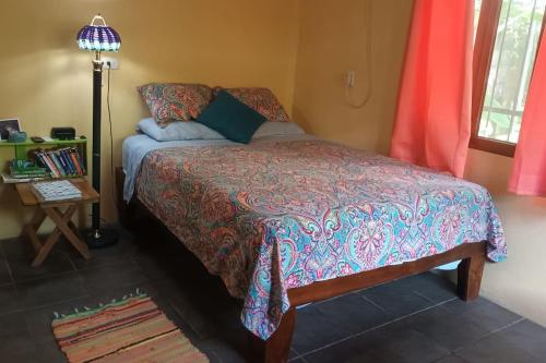 1 dormitorio con cama, lámpara y ventana en Casita Olivia en Sámara
